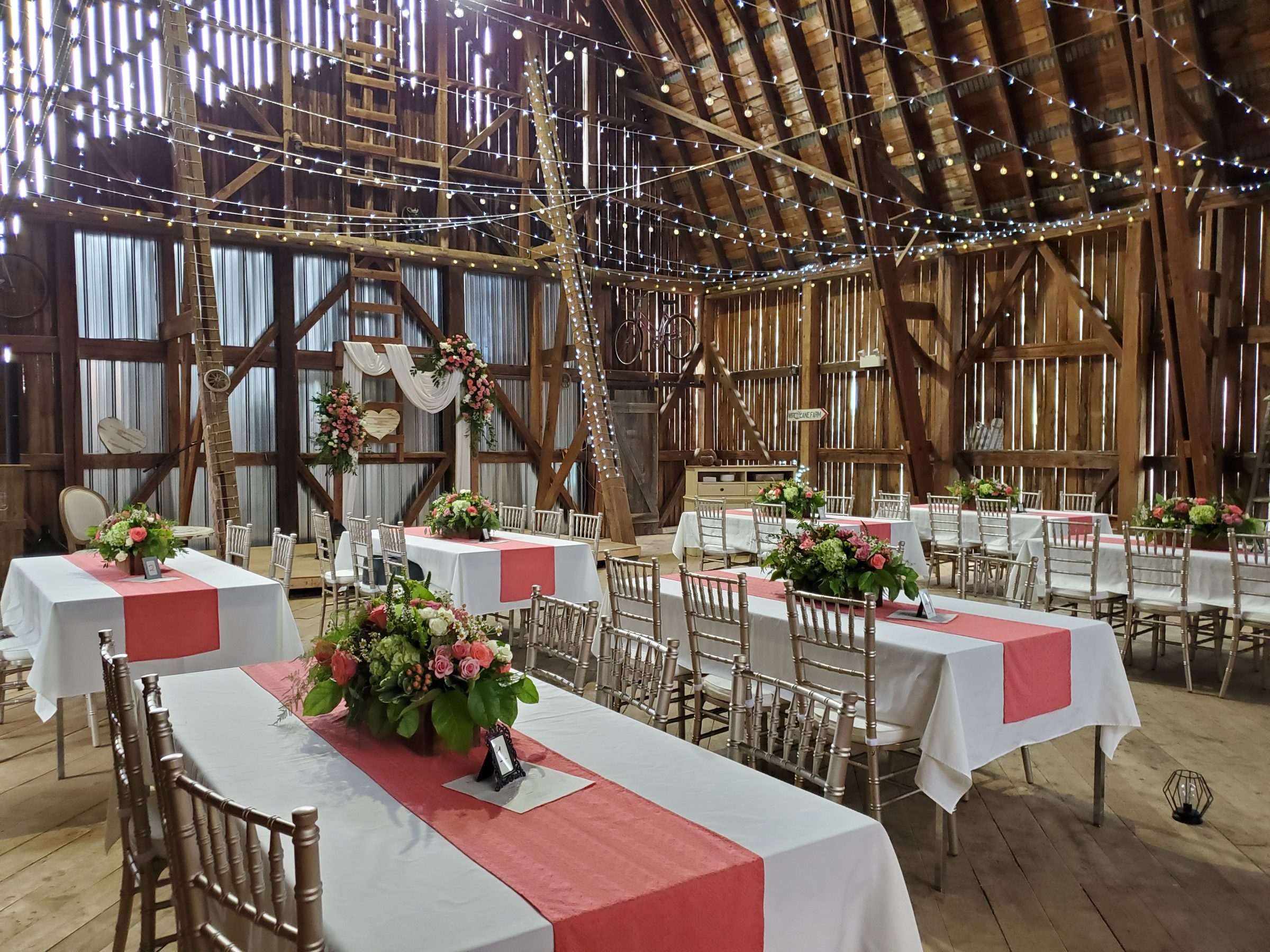 Barn interior set for reception with coral runners and fairy lights