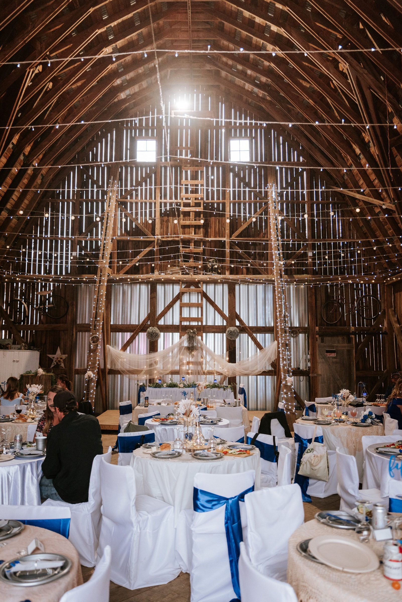 Full reception view with tables, string lights cascading from the rafters