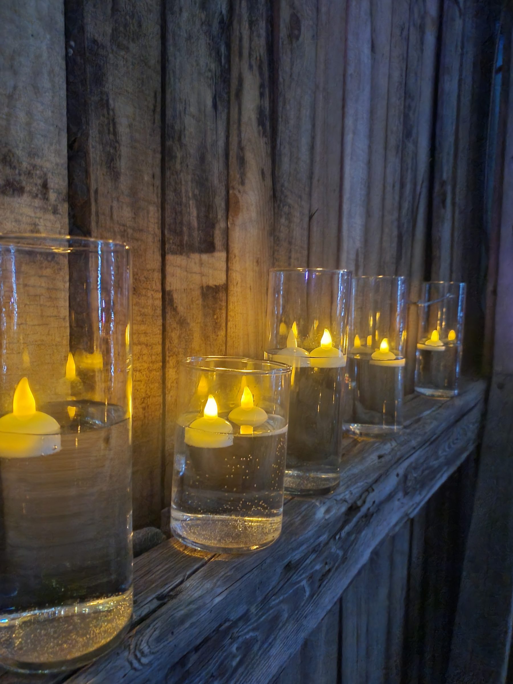 Warm candlelight on aged wooden barn surface